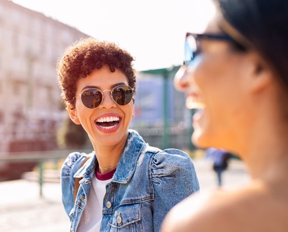 Happy relaxed women talking and laughing while walking in the city centre