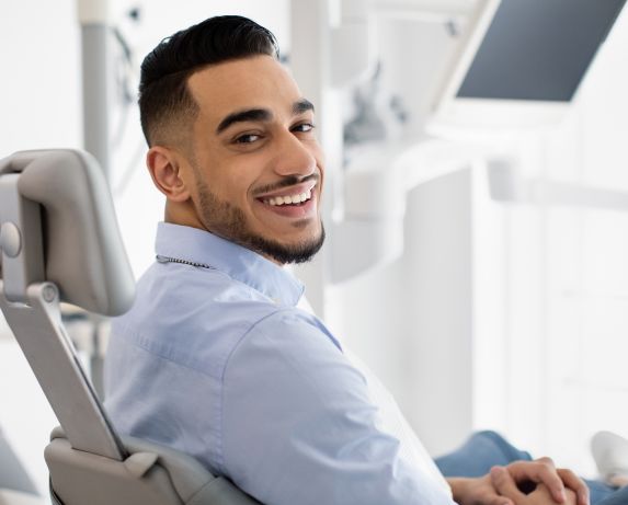 Happily smiling man in a dental chair after treatment
