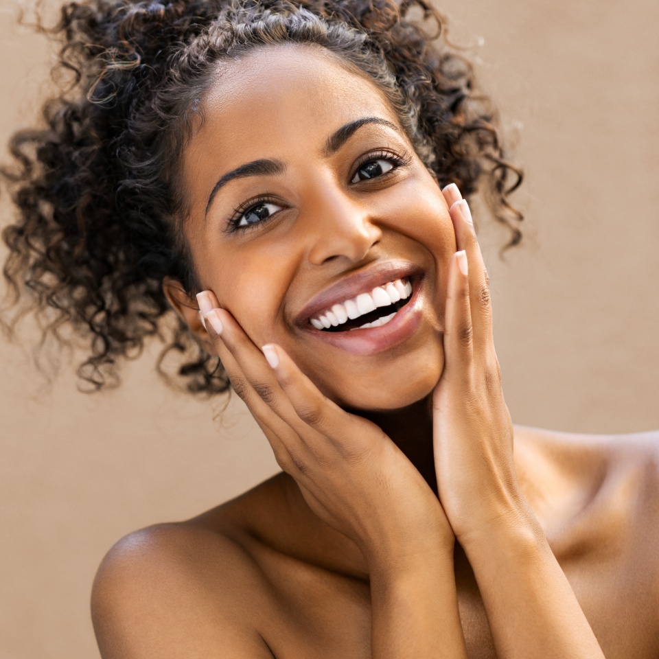 Beautiful young woman smiling after fantastic face treatment. Happy beauty african girl excited after spa treatment isolated on background with copy space. Surpise and astonishment beauty concept.