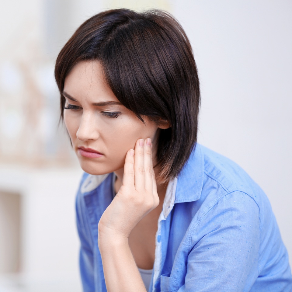 Beautiful young woman suffering from toothache at home