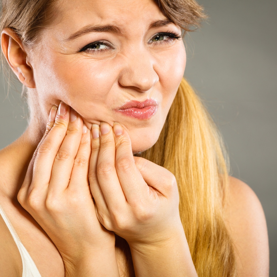 Dental care and toothache. Young woman achy girl suffering from terrible tooth pain touching pressing her cheek by hand palm.