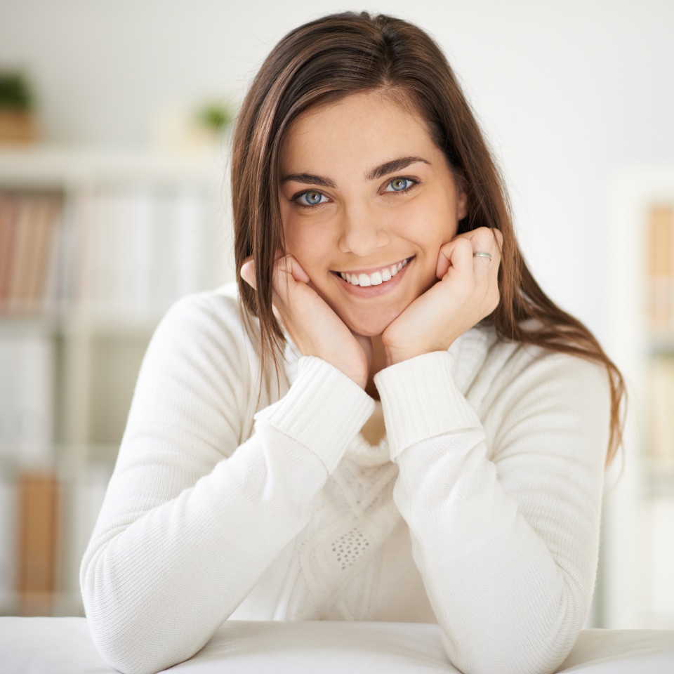 Happy girl in white pullover looking at camera with smile