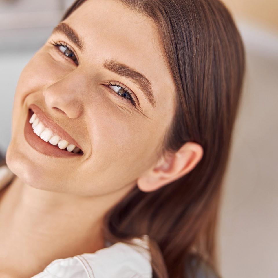 Attractive woman visiting dental clinic. Happy young woman sitting in dental chair at dentist office