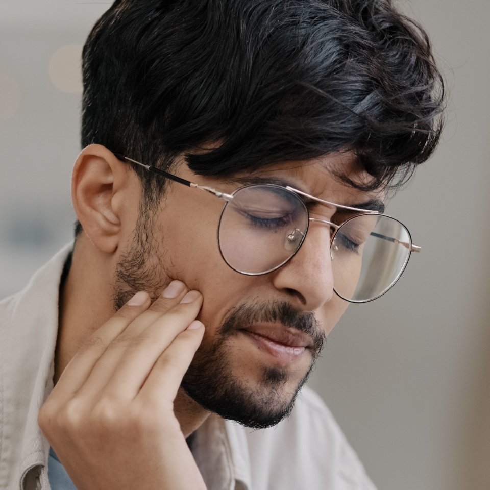 Close-up sick indian man in glasses male sad hispanic arab bearded man suffering tooth pain. Portrait guy feels toothache discomfort in gum caries holdong check with hand dental oral problem concept