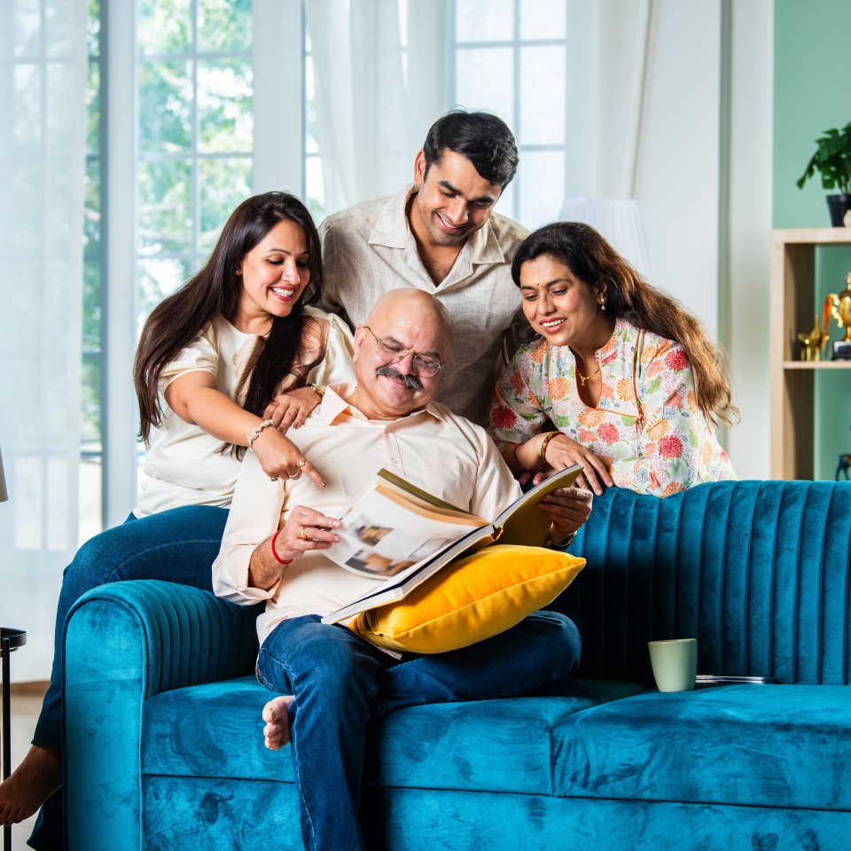 Indian family looking at Photo album while sitting on sofa, happy moment
