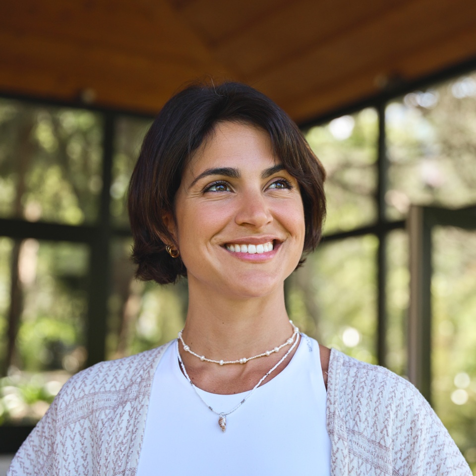 Young happy confident Hispanic woman health coach, yoga instructor, holistic teacher looking away standing in yoga studio advertising retreat mind body health therapy classes. Copy space.