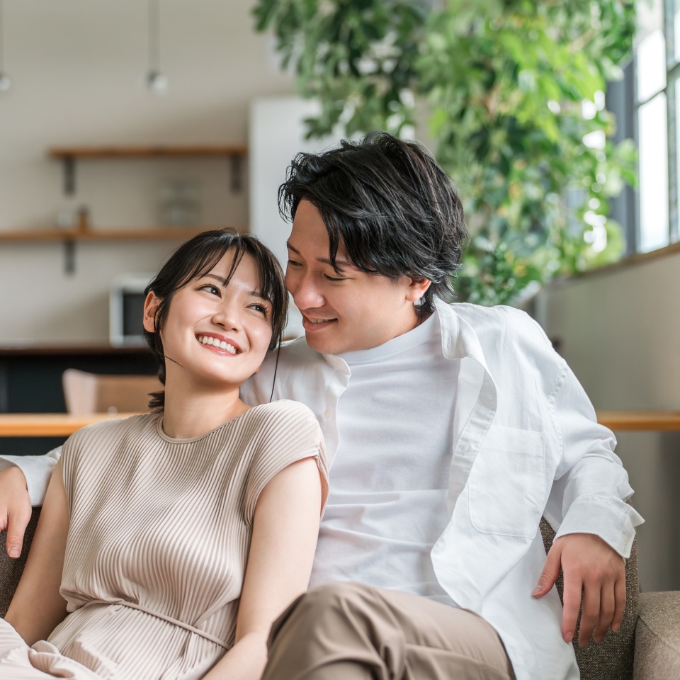 A friendly young Asian couple sitting on the sofa in the living room at home