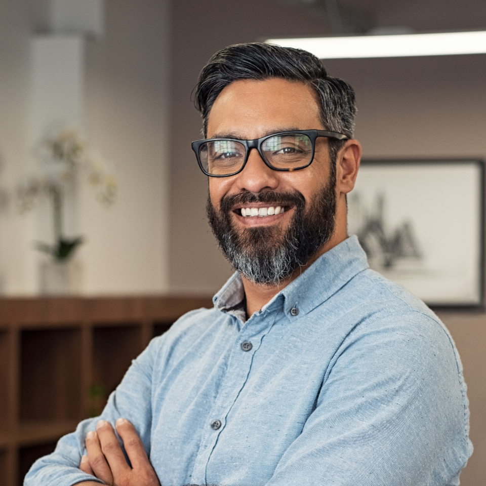 Portrait of happy mature businessman wearing spectacles and looking at camera. Multiethnic satisfied man feeling confident in a creative office. Successful middle eastern business man smiling.