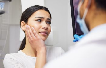 Young woman with dental pain and a dentist discussing the dental imaging and treatment