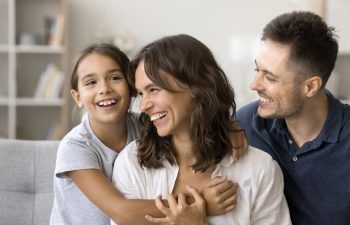 A man and woman smiling with a girl.