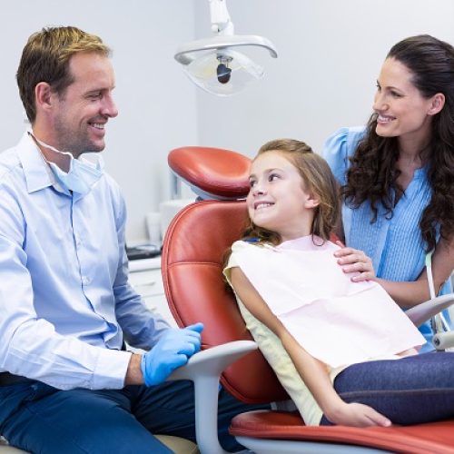Dentist,Interacting,With,Mother,And,Daughter,While,Dental,Examination,At