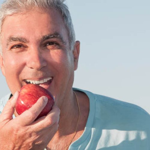 Portrait of a mature man about to eat a red apple